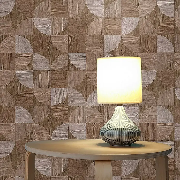 Tadessi Vliestapete M1-No.1572 - Beige, Sonstiges, 10,05 x 0,53 m - Eine beleuchtete Tischlampe mit geripptem Keramikfuß und Stoffschirm steht auf einem runden Holztisch vor einer gemusterten Wand.