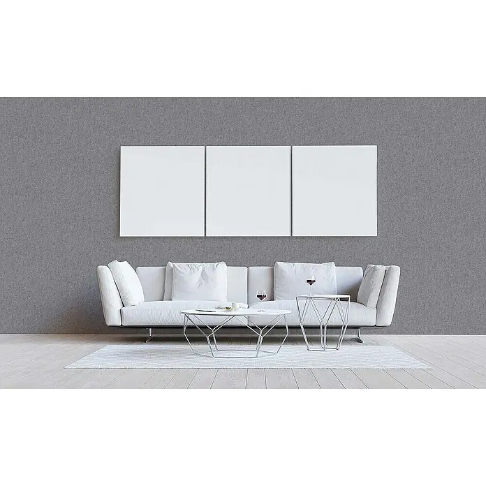 Tadessi Vliestapete M1-No.1813 - Grau, Steinoptik, 10,05 x 0,53 m - Drei leere weiße Leinwände hängen nebeneinander an einer grauen Wand über einem Sofa.