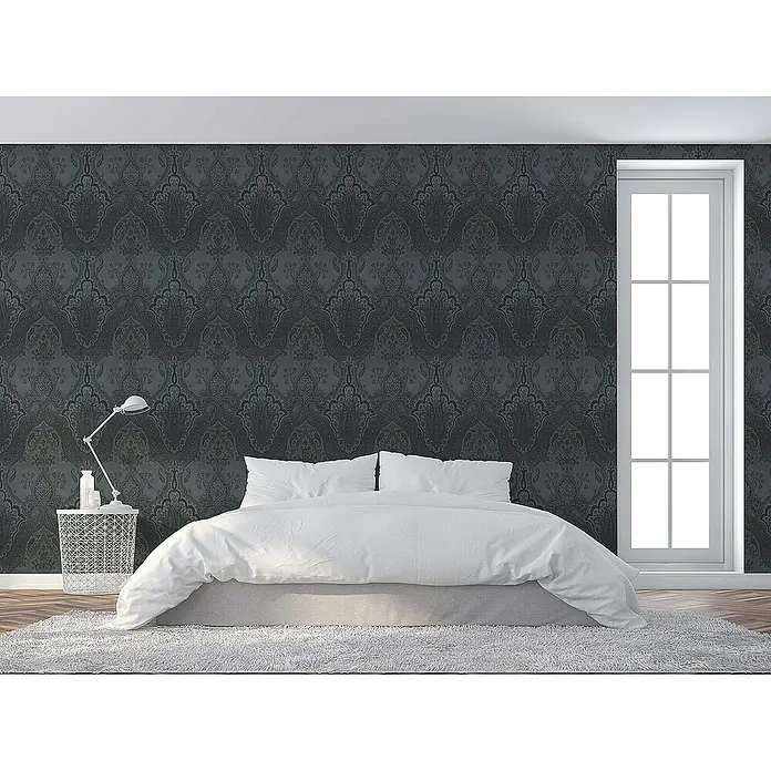 Tadessi Vliestapete M1-No.1855 - Schwarz, Ornament, 10,05 x 0,53 m - Dunkelgraue Tapete mit aufwendigem Damastmuster bedeckt eine Schlafzimmerwand über einem weißen Bett, neben einem Fenster.