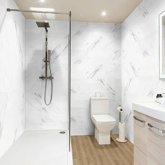 Revêt Wandpaneel SPC Wall - 600 x 300 mm, Marmor Weiß, Hochglänzend - Helles Badezimmer mit Marmorwänden, Dusche und Toilette. Die weißen Marmorfliesen sind das hervorstechende Merkmal dieses Bads.