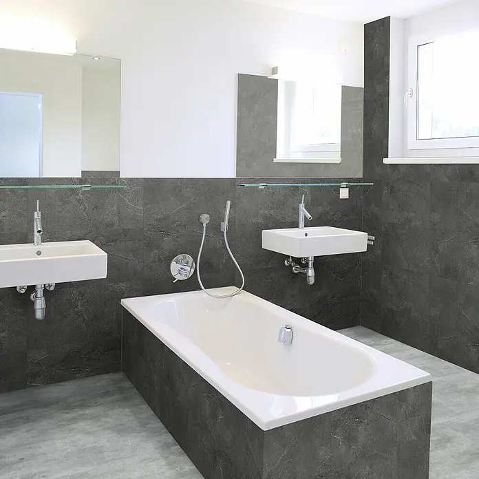 Revêt Wandpaneel SPC Wall - 600 x 300 mm, Schiefer - Das Badezimmer verfügt über eine moderne Badewanne, zwei Waschbecken und dunkle Marmorfliesen für einen stilvollen Look.