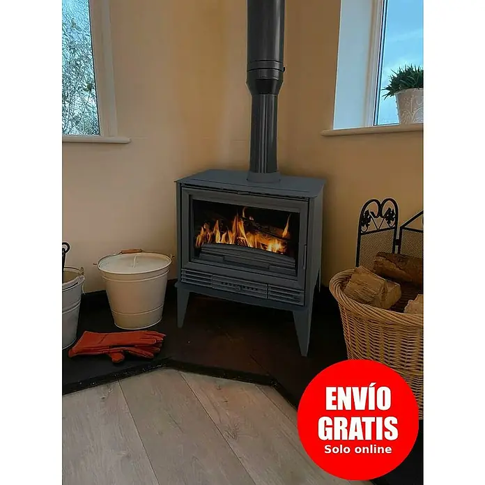 Invicta Estufa de leña Padua sin ventiladores - 10 kW, Volumen de calefacción: 300 m³, sin ventiladores, Negro - Una estufa de leña de hierro fundido con un tubo de chimenea, colocada en una habitación acogedora. Una pegatina roja con "Envío gratuito" en la imagen.
