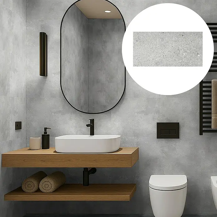 Revêt Wandpaneel SPC Wall - 600 x 300 mm, Beton Grau - Ein modernes Badezimmer mit grauen Wandfliesen, einem ovalen Spiegel und einem schwebenden Holzwaschtisch. Die Fliesen haben eine feine, gesprenkelte Textur.