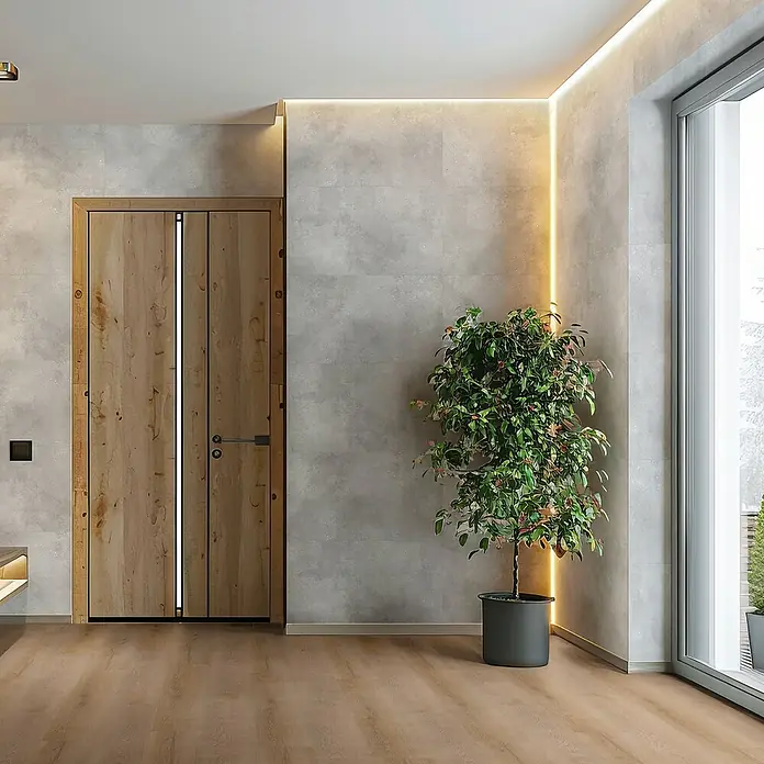 Revêt Wandpaneel SPC Wall - 600 x 300 mm, Beton Grau - Diese Aufnahme zeigt eine moderne Holztür mit einem schlanken, senkrechten Lichtakzent, ergänzt durch eine Zimmerpflanze in einem stilvollen, dunklen Topf.