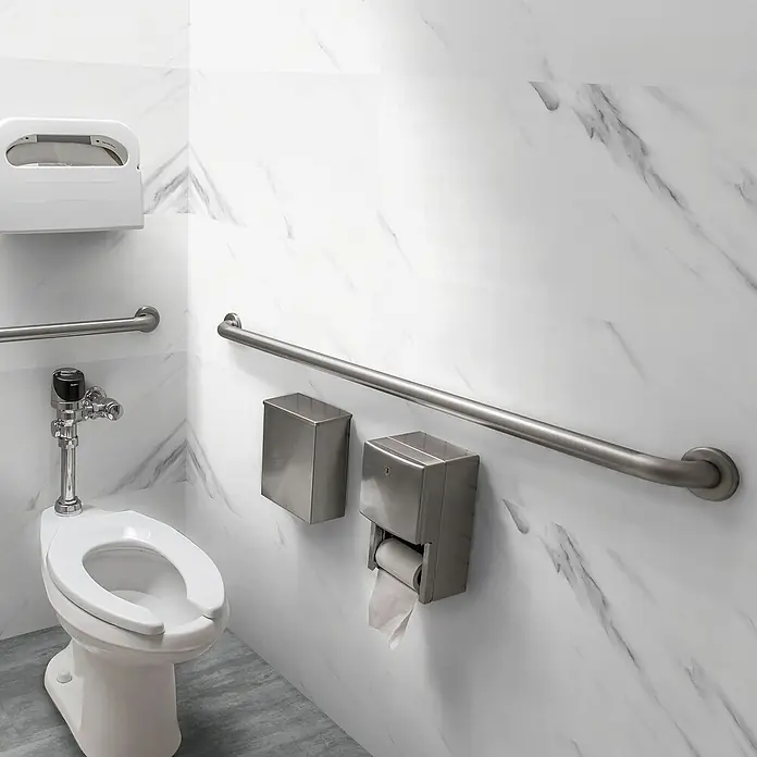 Revêt Wandpaneel SPC Wall - 1.200 x 600 mm, Marmor Weiß, Hochglänzend - WC-Bereich mit Haltegriff, Toilettenpapierspender und Abfalleimer. Die Marmorwand und der graue Boden verleihen dem Raum ein modernes Aussehen.