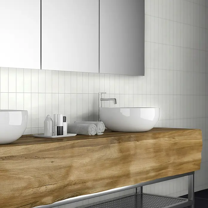 Revêt Wandpaneel SPC Wall Butcherblock - 1.200 x 600 mm, Weiß, Hochglänzend - Elegantes Badezimmer mit Holztisch, Aufsatzwaschbecken und stilvollen Accessoires. Die weißen Fliesen runden das moderne Design ab.