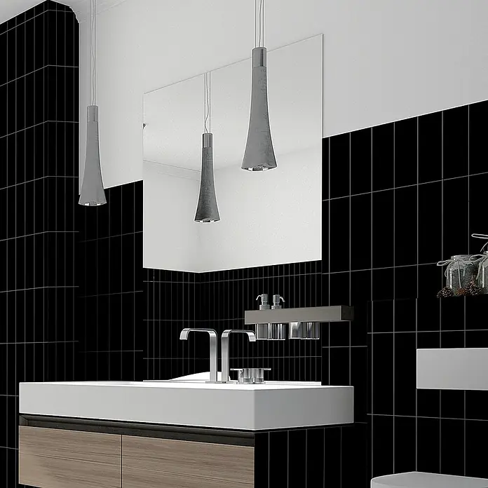 Revêt Wandpaneel SPC Wall Butcherblock - 1.200 x 600 mm, Schwarz, Hochglänzend - Schwarze Fliesen zieren ein modernes Badezimmer mit weißem Waschtisch und Spiegel, akzentuiert durch elegante Pendelleuchten.