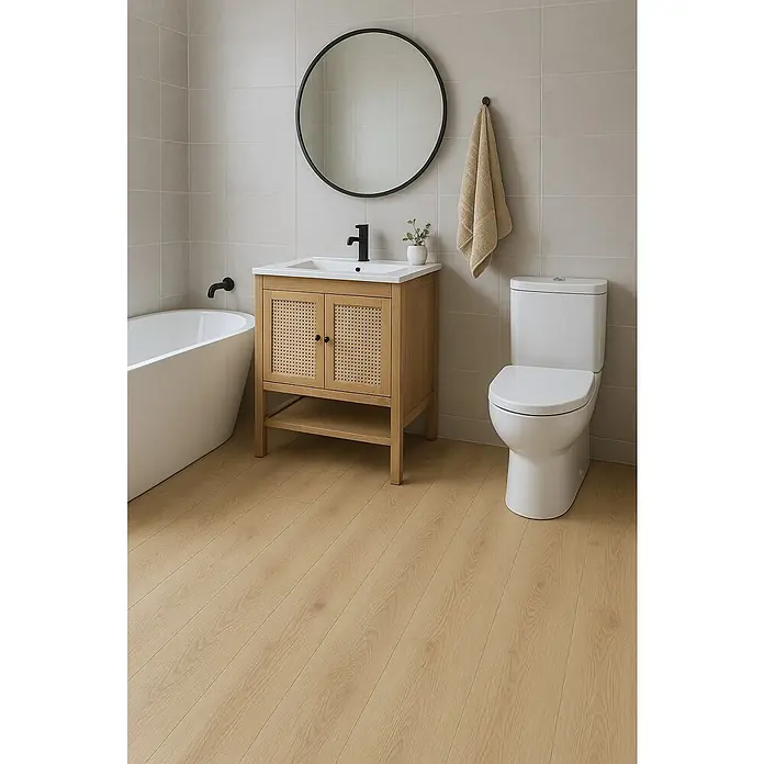 Suelo vinílico SPC Mana - 1.222 x 182 x 1,5 mm, Marrón, Resistente al agua - Escena de baño con un tocador con puertas de ratán, un espejo redondo y un inodoro blanco.