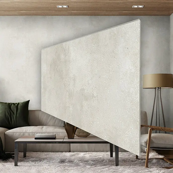 Revêt Wandpaneel SPC Wall - 1.200 x 600 mm, Beige - Wohnzimmeransicht mit beigem Sofa, Couchtisch, Sessel, Stehlampe und einer großen beigen Wand, die als Raumteiler dient.