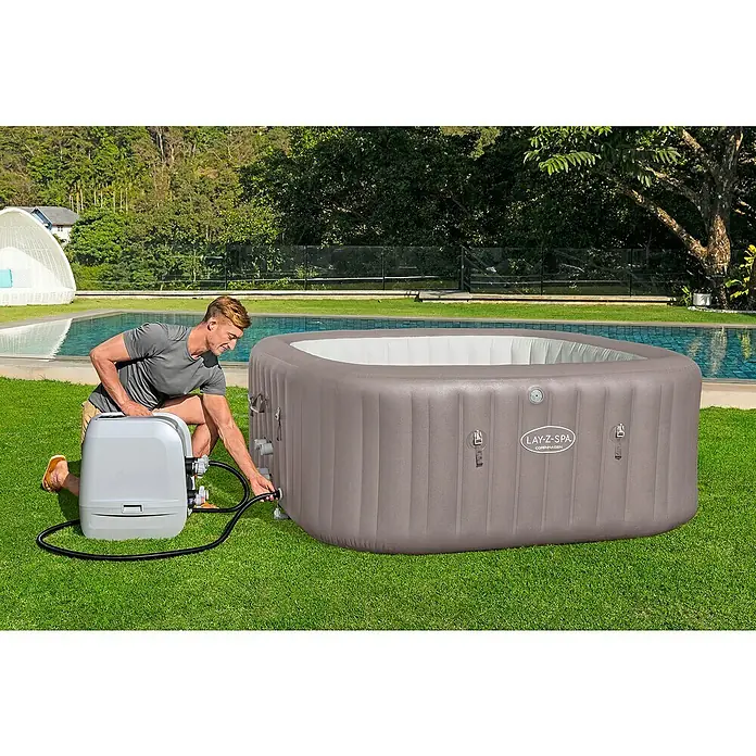 Bestway Lay-Z-Spa Mobil-Whirlpool Copenhagen Hydrojet - L x B x H: 201 x 201 x 80 cm, Grau, 1.050 l - Mann installiert einen Lay-Z-Spa Whirlpool im Freien. Der Whirlpool ist grau und hat ein rechteckiges Design, ideal zum Entspannen.