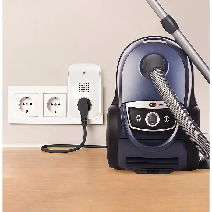 Heidemann Funkempfänger HX Curve - Weiß - Ein Staubsauger der an einer smarten Steckdose angeschlossen ist, steht auf einem Holzboden vor einer Wand.