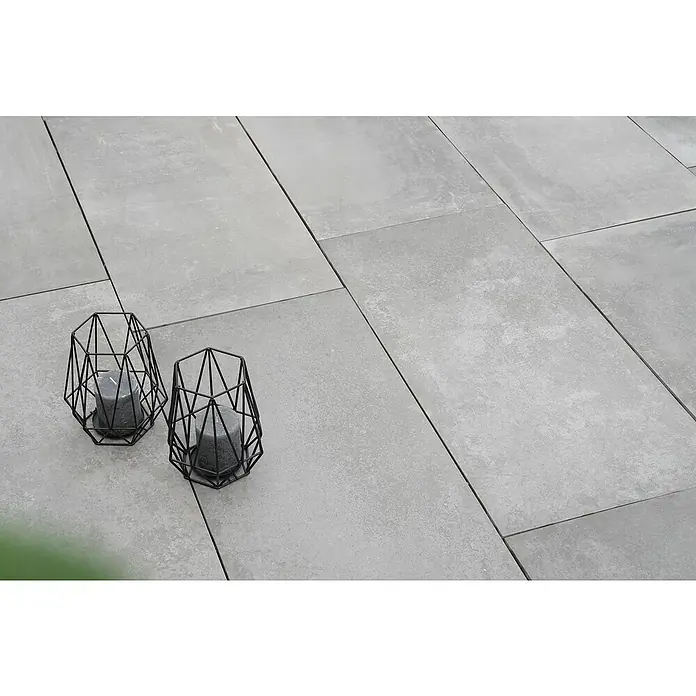 Diephaus Terrassenplatte Columbia - 80 x 40 x 4 cm, Fusion Basalt, Beton - Zwei dekorative, schwarze Kerzenhalter mit grauen Kerzen stehen auf einer grauen Steinterrasse und sorgen für eine gemütliche Atmosphäre.