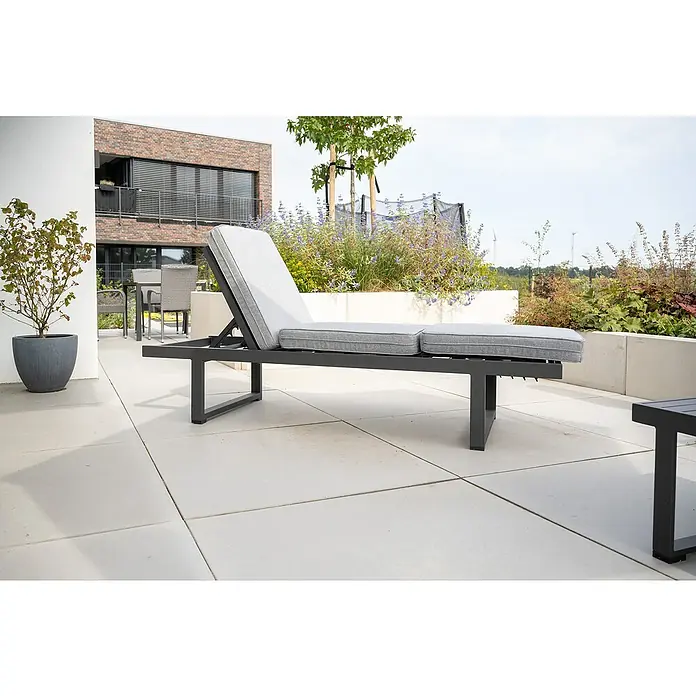 Diephaus Terrassenplatte Edison - 100 x 100 x 4 cm, Grau, Beton - Eine graue Sonnenliege mit verstellbarer Rückenlehne und bequemen Auflagen steht auf einer Terrasse. Das elegante Design lädt zum Entspannen im Freien ein.