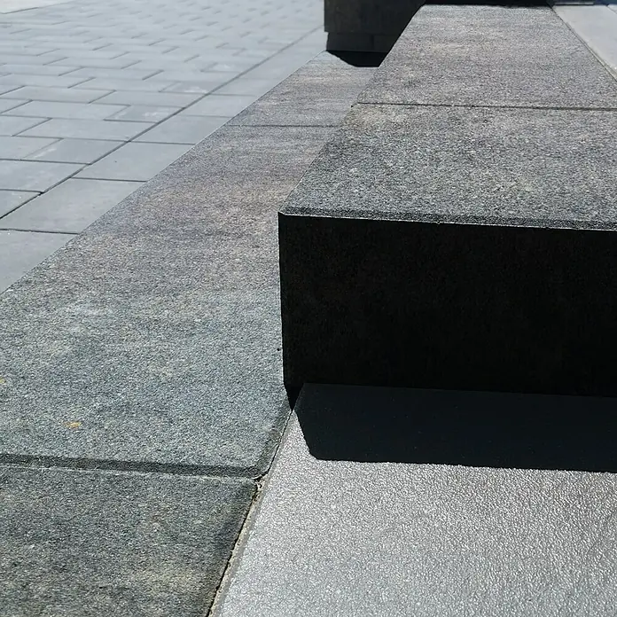 Diephaus Blockstufe Niles - 100 x 35 x 15 cm, Quarzit, Beton - Nahaufnahme von grauen Pflastersteinen mit dunklen Akzenten, die ein modernes und minimalistisches Design aufweisen. Ideal für Außenbereiche.