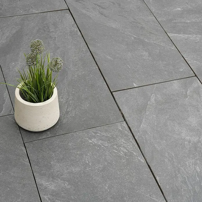 Diephaus Terrassenplatte Columbia - 80 x 40 x 4 cm, Core Basalt, Beton - Nahaufnahme von stilvollen grauen Bodenfliesen mit einer dekorativen Topfpflanze für den Außenbereich, die eine moderne und elegante Atmosphäre schafft.