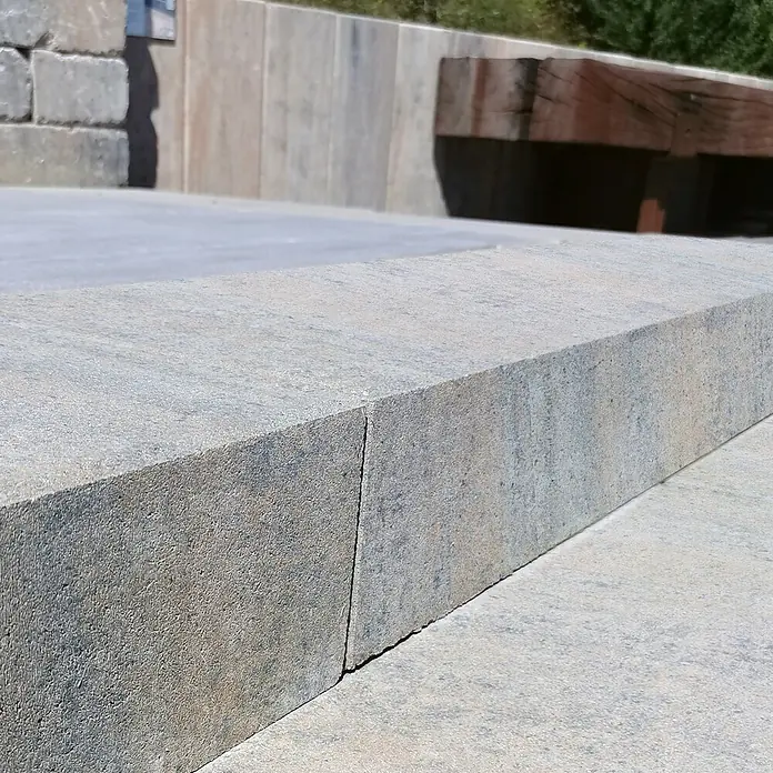 Diephaus Blockstufe Niles - 100 x 35 x 15 cm, Muschelkalk, Beton - Nahaufnahme von zwei grauen Pflastersteinen, die eine robuste und moderne Gartengestaltung zeigen.\n