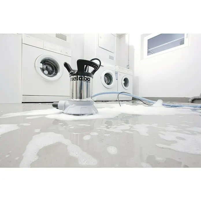 Metabo Klarwasser-Tauchpumpe 6600 SN - Max. Fördermenge: 6.600 l/h - Der Fokus liegt auf einer Metabo TPF 6600 SN Schmutzwasserpumpe, die in einem überfluteten Raum mit Waschmaschinen aufgestellt ist.