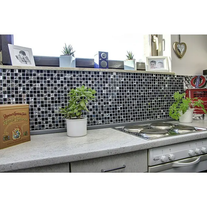 Selbstklebemosaik SAM 4CM26 - 30 x 30 cm, Mix Schwarz, Glänzend - Küchenansicht mit Herd, Arbeitsplatte und dekorativen Elementen wie Pflanzen und Fliesen, die eine wohnliche Atmosphäre schaffen.