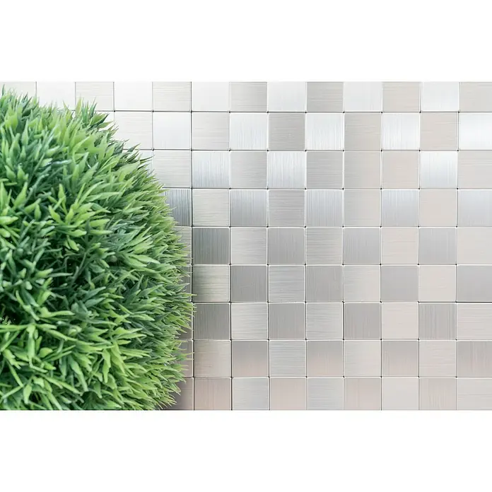 Selbstklebemosaik SAM 4MM25 - 30,5 x 30,5 cm, Silber, Glänzend - Nahaufnahme eines modernen Hintergrunds mit silbernen Metallfliesen und einer grünen Pflanze, der elegante Designelemente zeigt.