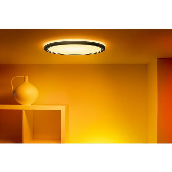 Philips Wiz Smart-LED-Deckenleuchte rund Tunable White & Color SuperSlim - 22 W, Ø x H: 42 x 4,3 cm, Schwarz, RGBW - Diese Aufnahme zeigt eine runde Deckenleuchte mit schwarzem Rand, die ein warmes Licht ausstrahlt und eine gemütliche Atmosphäre erzeugt.
