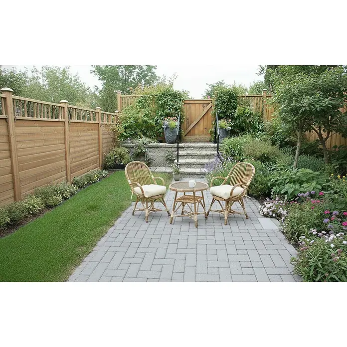 Andrewex Sichtschutzelement Rosette - B x H: 180 x 180 cm, Kiefer Natur - Zwei Rattanstühle und ein Tisch auf einer Terrasse mit Blick auf einen üppigen Garten, die eine gemütliche und einladende Atmosphäre schaffen.
