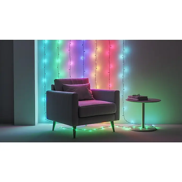 WiZ Smart-LED-Lichterkette - Innen, 20 m, Lichtfarbe: Mehrfarbig, 160 Stk. - Einrichtungsidee mit farbwechselnden LED-Lichtern an der Wand, Akzentsessel und Beistelltisch mit Büchern und Brille.