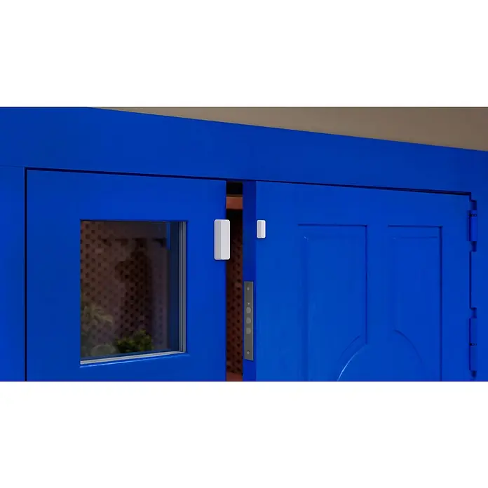 WiZ Fenster- & Türsensor - L x B x H: 7,65 x 2,25 x 2,25 cm - Nahaufnahme einer blauen Tür mit installiertem Türsensor, der für Sicherheit sorgt und den Zutritt überwacht.