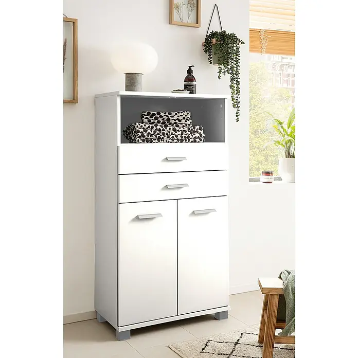 Schildmeyer Palermo Highboard - B x T x H: 60 x 32,6 x 110,5 cm, Weiß, Matt - Aufnahme eines weißen Badezimmerschranks mit zwei Schubladen und zwei Türen, auf dem Handtücher und eine Lampe liegen.