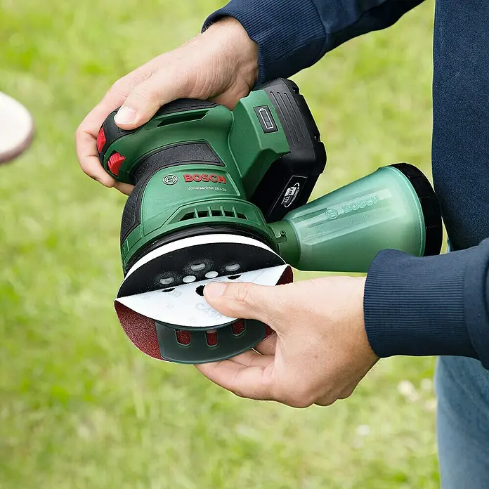Bosch Power for All 18V Akku-Exzenterschleifer UniversalOrbit 18V-20 - 18 V, Ohne Akku, Durchmesser Schleifteller: 125 mm - Ein grüner Bosch Universal Orbit 18V-125 Akku-Exzenterschleifer mit Staubabsaugung wird von einer Person gehalten.
