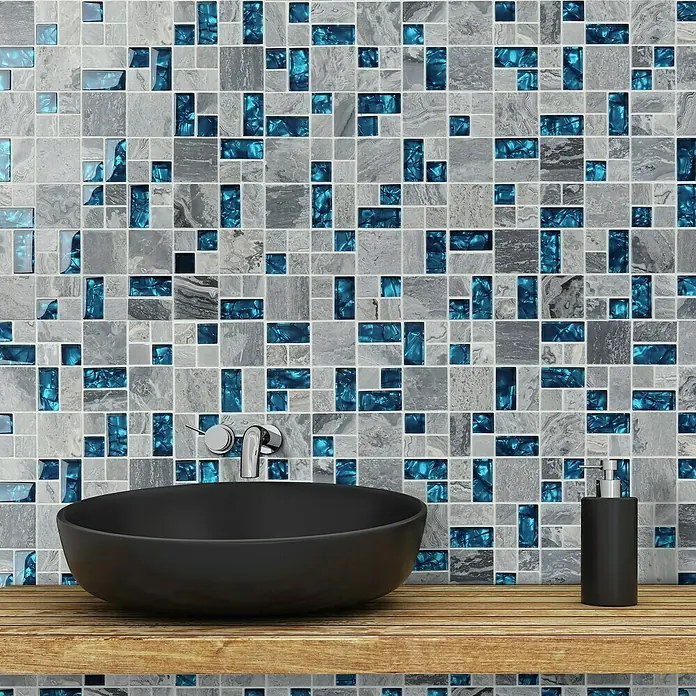 Mosaikfliese Crystal Mix XCM MC589 - 30 x 30 cm, Grau, Glänzend - Elegantes Waschbecken und Seifenspender vor einer Mosaikwand mit blauen Akzenten. Das Waschbecken und der Spender stehen auf einem Holzregal.
