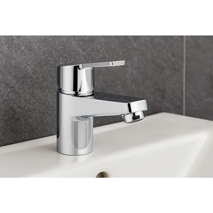 Clever Eno-X Grifo de lavabo 60 - Cromo, Brillante - Primer plano de un elegante grifo cromado sobre un lavabo blanco contra una pared gris.