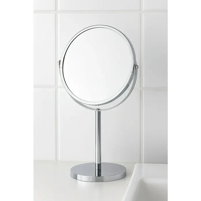 Venus Espejo cosmético Lina - Diámetro: 15 cm, Redonda, Cromo, Aumento 1: 300 % - Primer plano de un espejo de tocador redondo cromado sobre una encimera de baño con azulejos blancos al fondo.