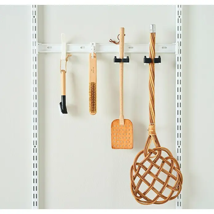 Elfa Garage+ by Elfa Haken - L x B x H: 9,4 x 2,3 x 7,2 cm, 3 Stk., Weiß - Eine Auswahl an Reinigungsutensilien, darunter Bürsten und ein Teppichklopfer, hängen ordentlich an einer weißen Wandhalterung.