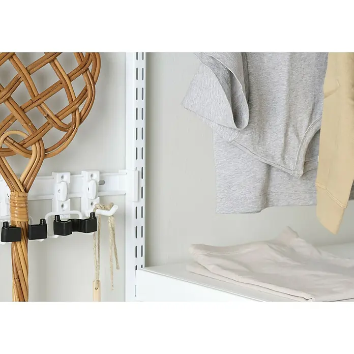 Elfa Garage+ by Elfa Beschlag-Set - Weiß, 2 Stk. - Nahaufnahme eines Regalsystems mit Aufbewahrungslösungen, darunter ein Rattanbesen und Kleidung, die Organisation und Funktionalität vereinen.