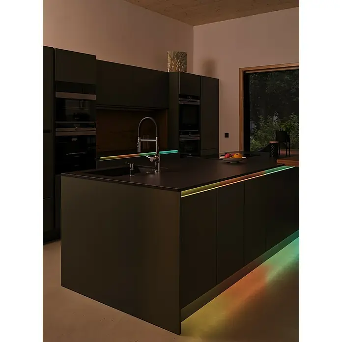 Osram Smart+ LED-Band COB - Länge: 500 cm, Lichtfarbe: RGB, 35 W, 220 V - 240 V - Dunkle Küche mit Kücheninsel und farbiger Beleuchtung unterhalb der Arbeitsfläche und im Sockelbereich.