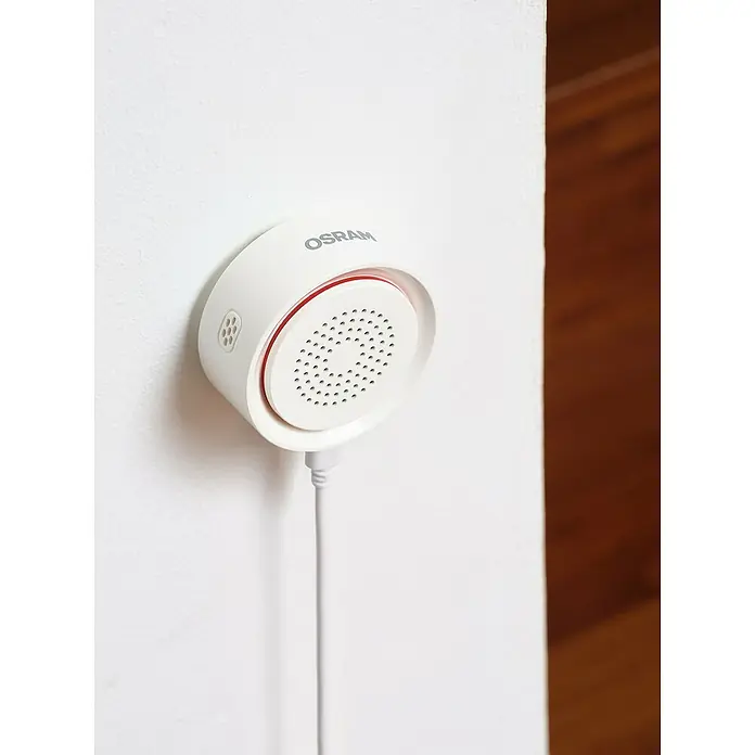 Osram Smart+ Alarmsirene - Innen, 90 dB, Netzbetrieben - Weißer OSRAM Smart+ Bewegungsmelder mit rotem Ring, an einer Wand befestigt, mit Kabel für intelligentes Zuhause.