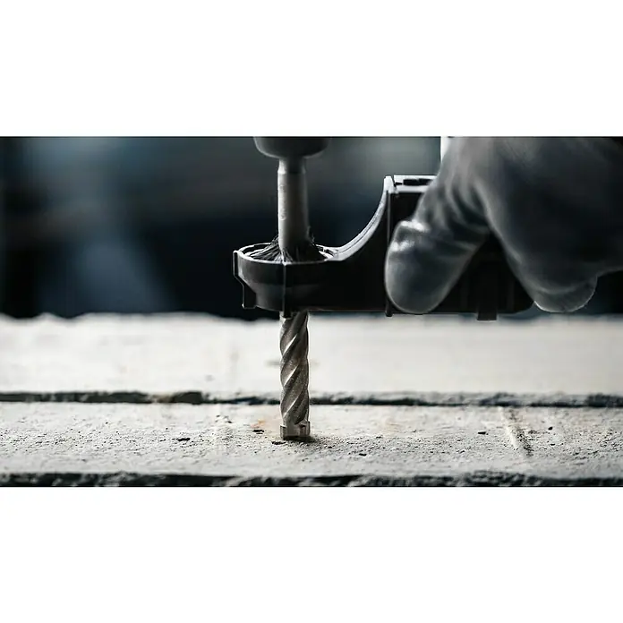 Bosch Beton- & Steinbohrer PRO SDS plus-5X - 1 Stk., Durchmesser Bohrer: 15 mm, Arbeitslänge: 200 mm - Eine Nahaufnahme einer Bohrmaschine mit Bohrer, die in eine Betonoberfläche bohrt. Ein behandschuhter Arbeiter hält die Maschine fest.