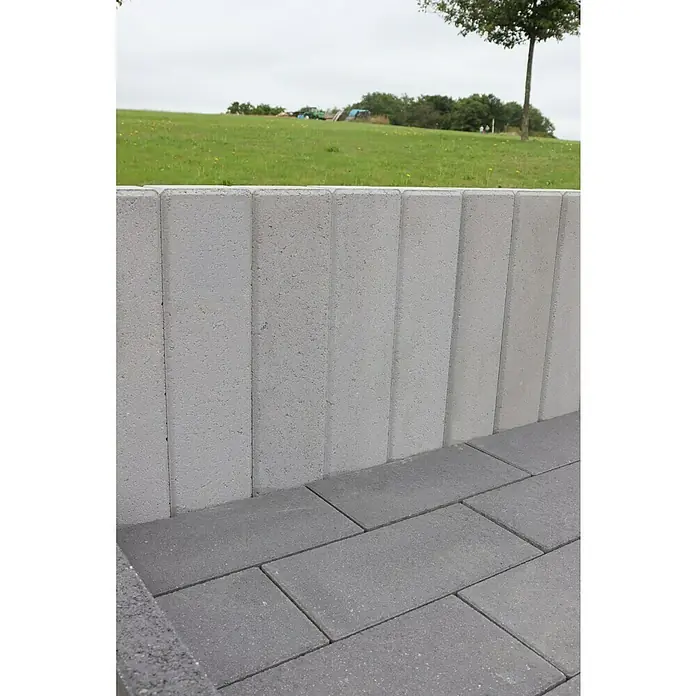 Christoph C-Line Palisade XL - 60 x 15 x 10 cm, Silbergrau, Beton - Nahaufnahme einer grauen Steinmauer und eines gepflasterten Bodens, die ein modernes Landschaftsdesign mit Fokus auf die Textur der Steine zeigen.