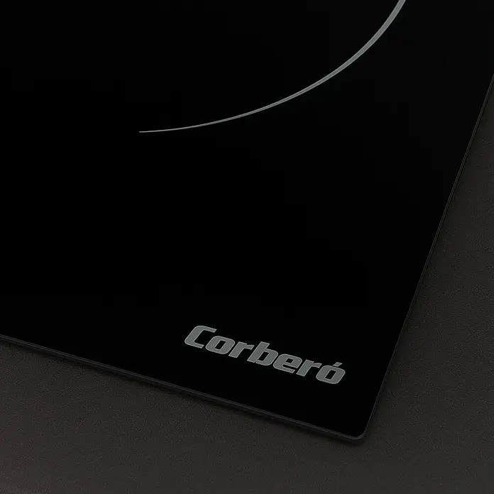 Corberó Placa de cocción CCIG3BL604 - L x An: 52 x 59 cm, Número de fogones de inducción: 3 ud. - Primer plano de una placa de cocción Corberó negra, mostrando su diseño elegante y logotipo sutil.