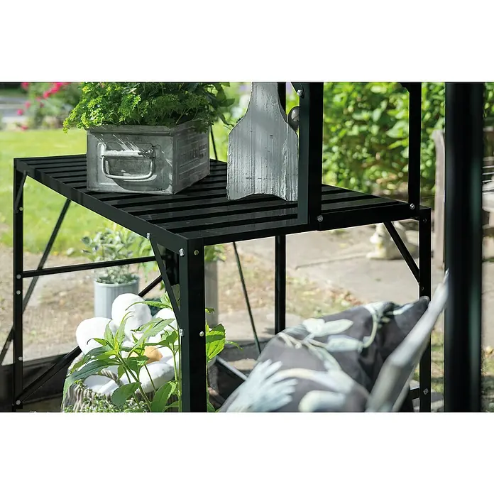 Halls Gewächshaus-Tisch 1 - 120,8 x 76 cm, Schwarz, Doppelte Ablageebene - Eine Nahaufnahme eines schwarzen Metallregals mit einer Pflanze und Dekorationen, die in einem Garten stehen.