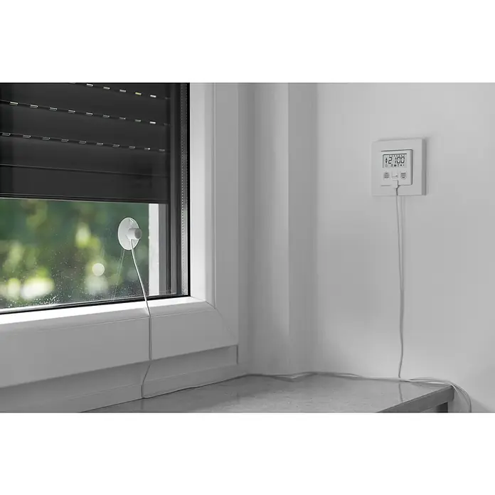 Schellenberg Sonnensensor Plus - Passend für: Schellenberg Zeitschaltuhr Plus, Kabellänge: 1,5 m - Innenaufnahme eines Fensters mit Rollladen und einem darauf befestigten Temperatursensor mit Kabel, daneben ein Raumthermostat.
