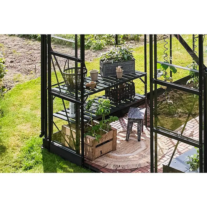 Halls Gewächshaus-Tisch - 120,8 x 76 cm, Grün, Doppelte Ablageebene - Detailansicht eines Gewächshauses mit Pflanzenregal, Pflanzgefäßen, einem kleinen Hocker und einem runden Teppich auf Holzboden.