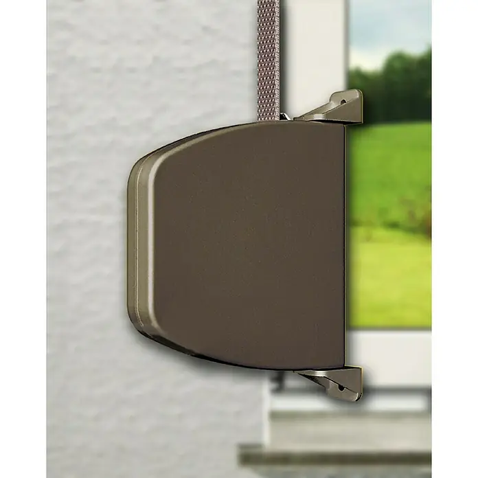 Schellenberg Aufschraubwickler Mini - L x B x H: 120 x 22 x 159 mm, Gurtbreite: 14 mm, Braun - Detailaufnahme einer braunen Jalousie mit Gurtwickler vor einem Fenster mit Blick ins Grüne.
