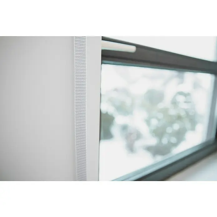 Schellenberg Rollladengurt Maxi - Weiß, Länge: 6 m, Gurtbreite: 23 mm - Detailaufnahme eines weißen Rollos neben einem Fenster, das einen verschwommenen Blick nach draußen bietet. Das Rollo zeichnet sich durch eine feine, textile Struktur aus.