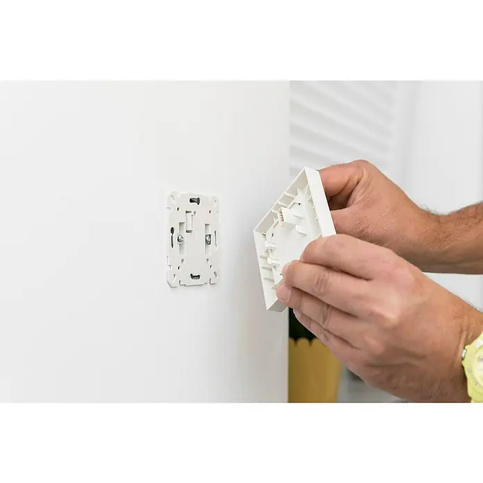 Schellenberg Smart Home Funk-Empfangsschalter - 80 x 80 x 40 mm, Weiß, Unterputzmontage - Detailaufnahme der Installation einer weißen Wandarmatur, zeigt die Montage durch eine Person mit Werkzeug.