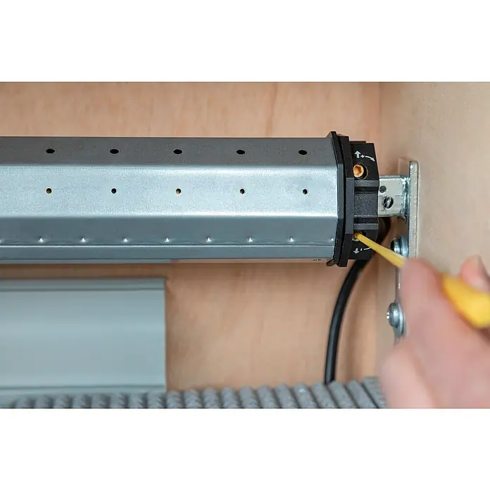 Schellenberg Rohrmotor Mini Standard 6 - Max. Rollladenfläche: 4 m² bei Kunststoffrollläden, Einbaulänge: 500 mm, Zugkraft: 15 kg - Einstellung eines Rollladenmotors mit Schraubendreher. Der Rollladenmotor ist silberfarben mit schwarzen Endkappen.