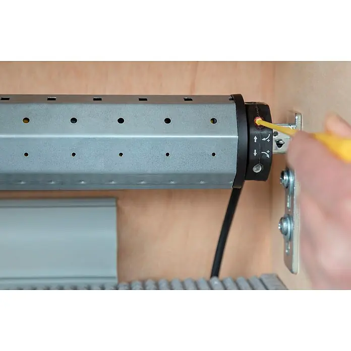 Schellenberg Rohrmotor Rollopower Action Mini 3 - Max. Rollladenfläche: 2 m² bei Kunststoffrollläden, Einbaulänge: 500 mm, Zugkraft: 8 kg - Nahaufnahme eines Rollladenmotors, der mit einem gelben Werkzeug justiert wird, wobei die Details des Einstellmechanismus deutlich sichtbar sind.