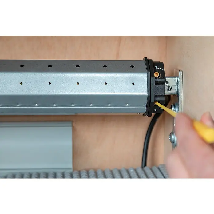 Schellenberg Rohrmotor Maxi Standard 10 - Max. Rollladenfläche: 4,2 m² bei Kunststoffrollläden, Einbaulänge: 500 mm, Zugkraft: 20 kg - Nahaufnahme einer Person, die mit einem gelben Schraubenzieher eine Rollladensteuerung justiert.