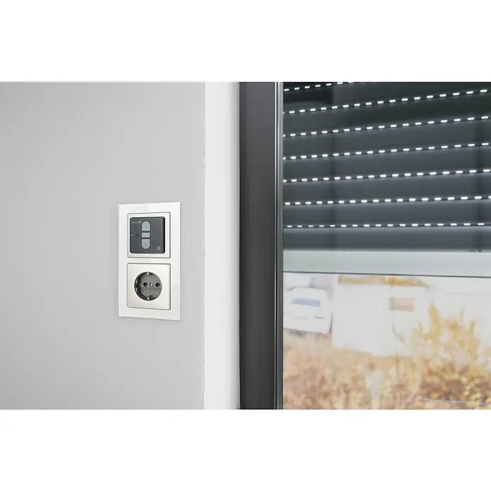 Schellenberg Smart Home Funk-Empfangsschalter - 40 x 80 x 80 mm, Anthrazit, Unterputzmontage - Nahaufnahme einer Doppelsteckdose und einem Rollladenschalter an einer Wand, kombiniert mit einem Fenster im Hintergrund.