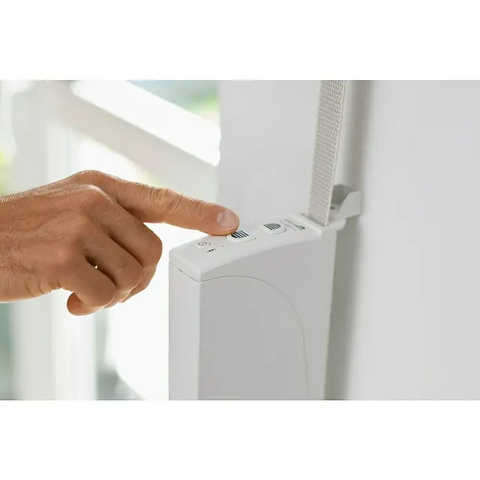 Schellenberg Rollladen-Gurtwickler Rollo Drive 35 - B x H: 38,5 x 199 mm, Gurtbreite: 14 mm, Zugkraft: 12 kg - Eine Nahaufnahme einer Hand, die einen Knopf an einem automatischen Rollladenmotor drückt, der an einer Wand montiert ist.